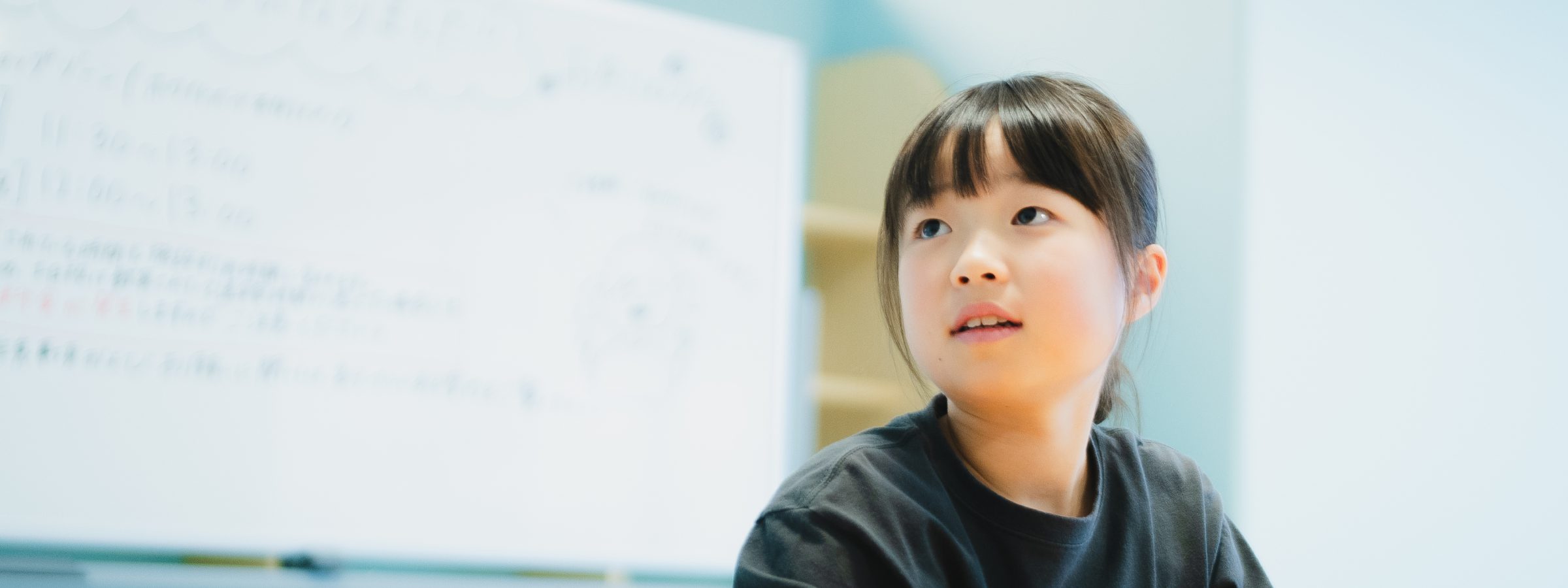 ホワイトボードの前で顔を上げる女の子