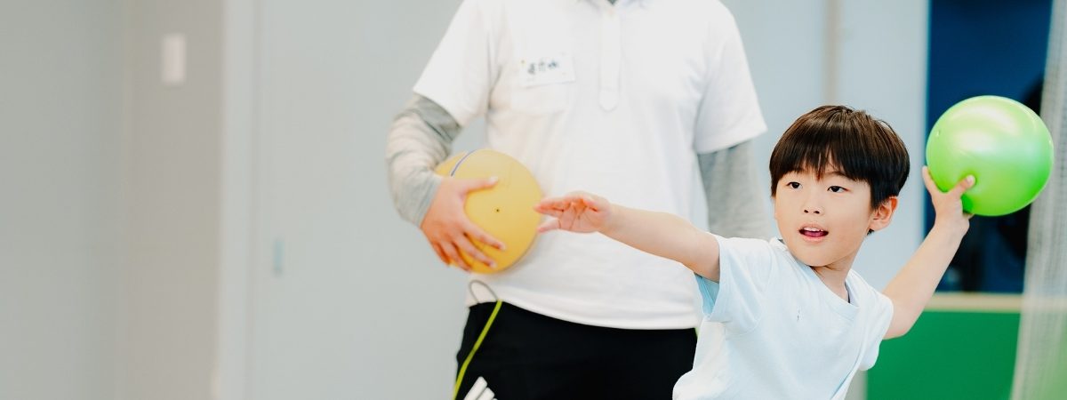 ボールを投げる子どもとコーチ