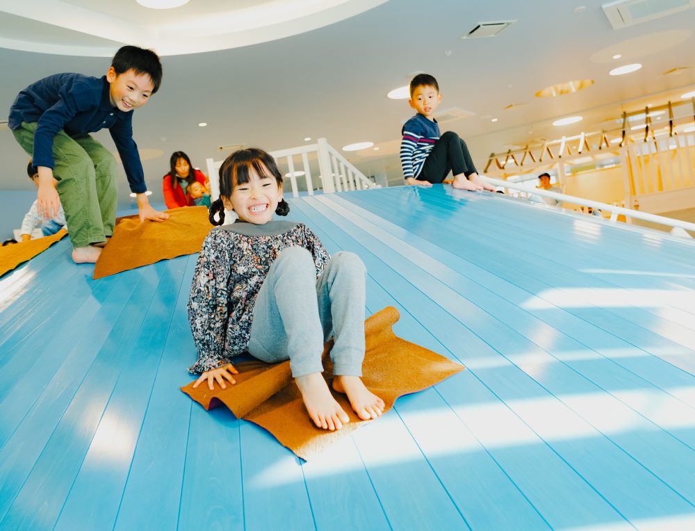すべり台をすべって笑う子どもたち