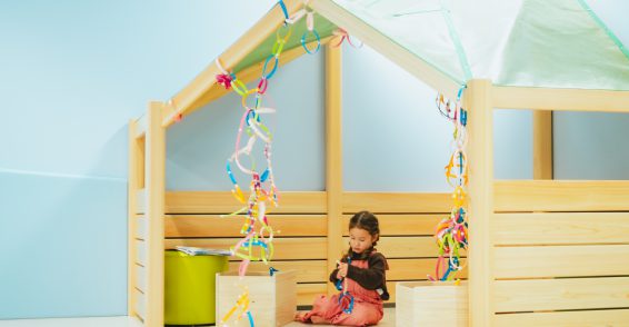 おうち型の遊具の中でひとり遊びをする女の子