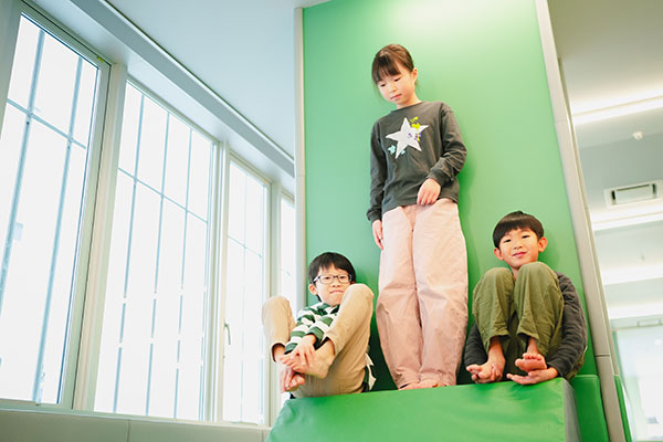 緑の壁の前に並ぶ子どもたち